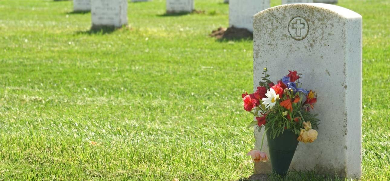 Graveyard With a Headstone and Colourful Flowers — Finlayson & McKenzie Funeral Directors in Rockhampton City, QLD