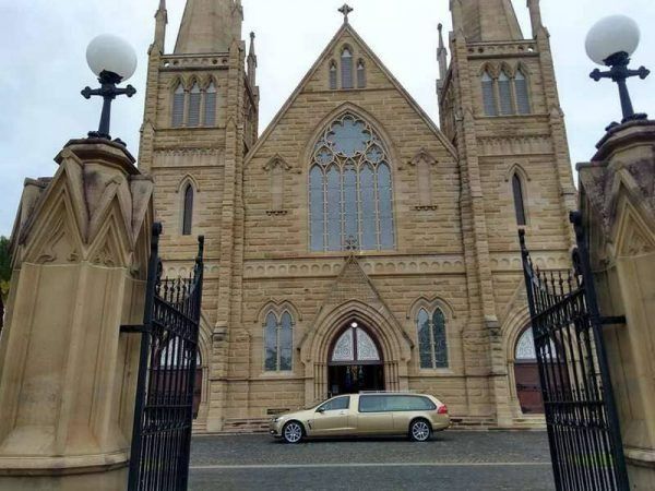 Church with Beige Stone Facade and Black Wrought-Iron Gates — Finlayson & McKenzie Funeral Directors in Rockhampton City, QLD