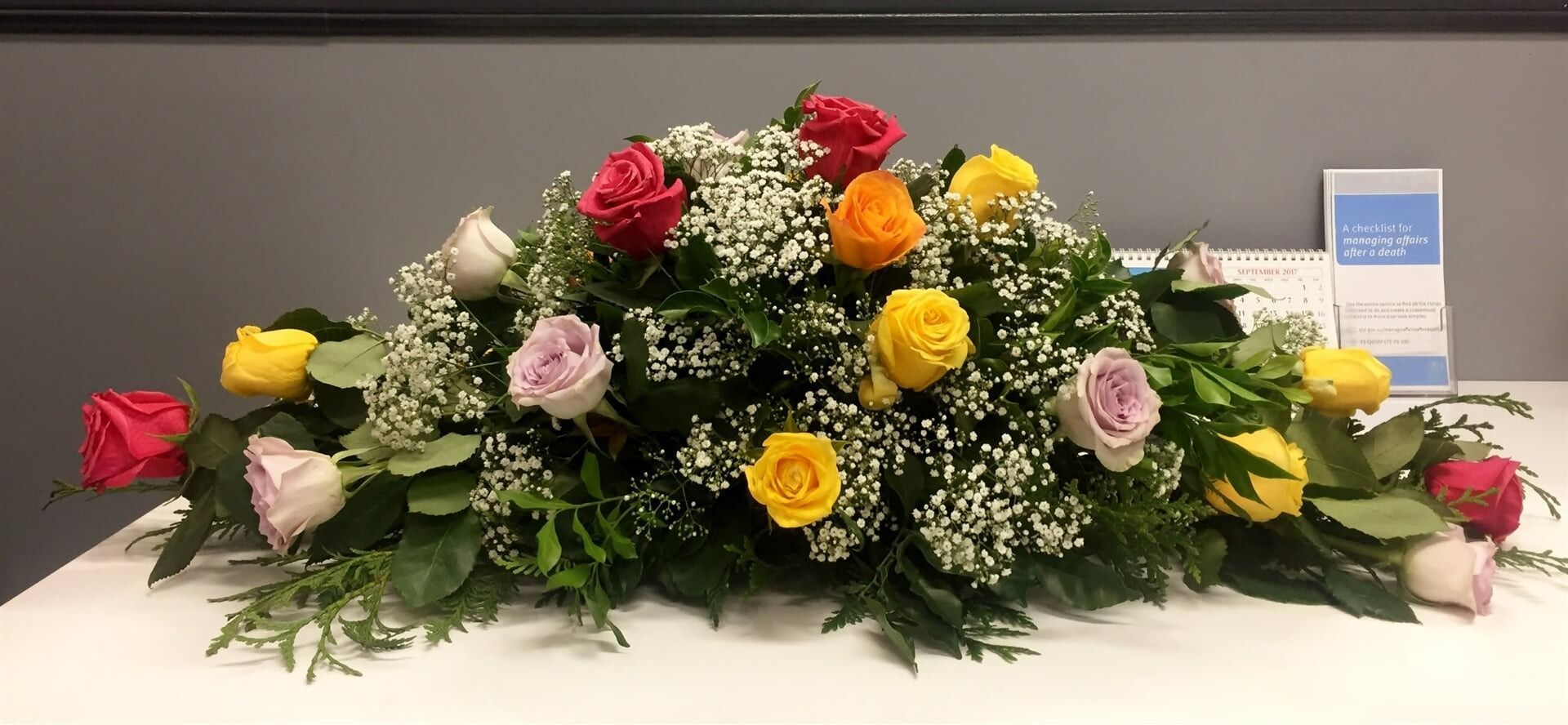 A Long Floral Arrangement of Colourful Roses — Finlayson & McKenzie Funeral Directors in Rockhampton City, QLD