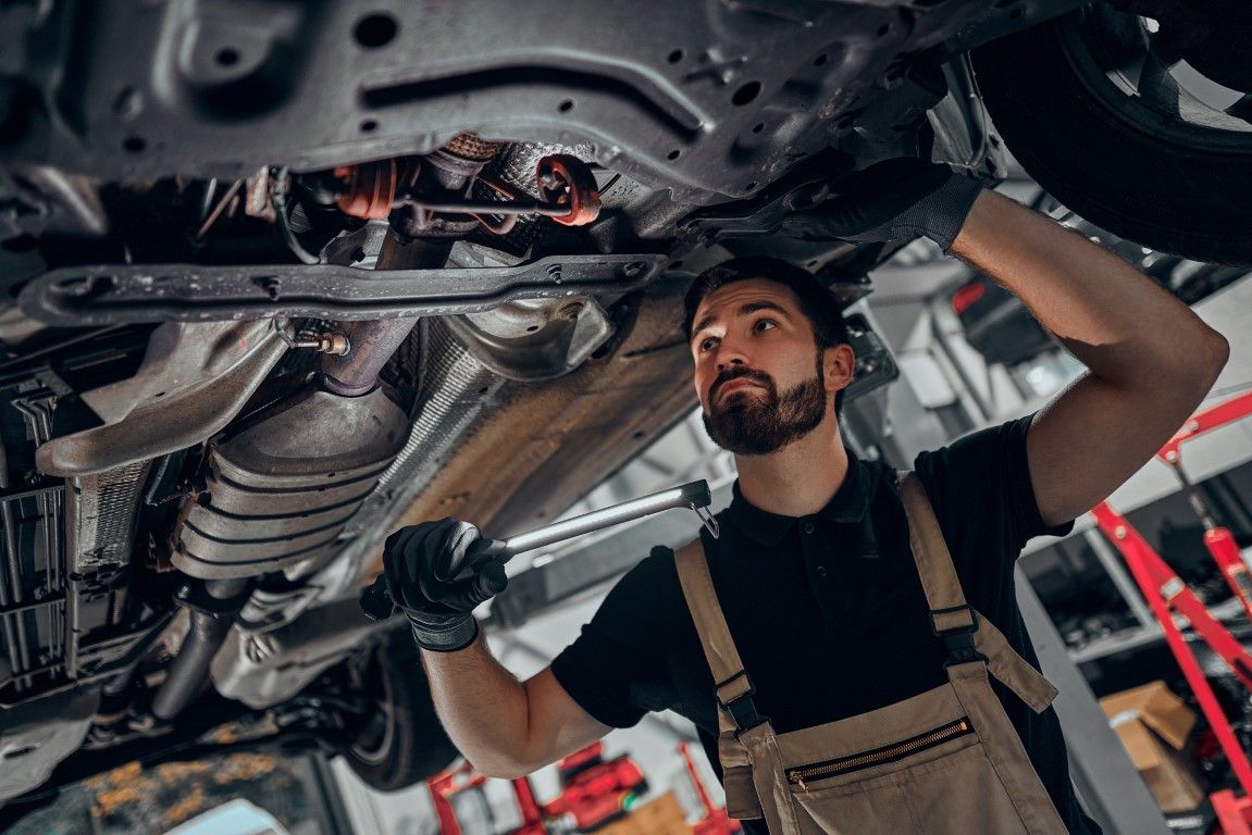 Mechanic inspecting the underside of a car on a lift in an auto repair shop