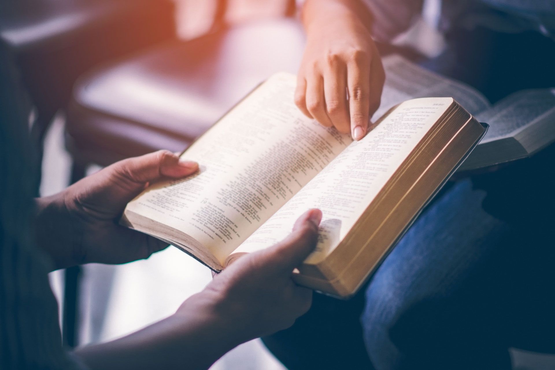 Hands pointing to an open book in a softly lit setting