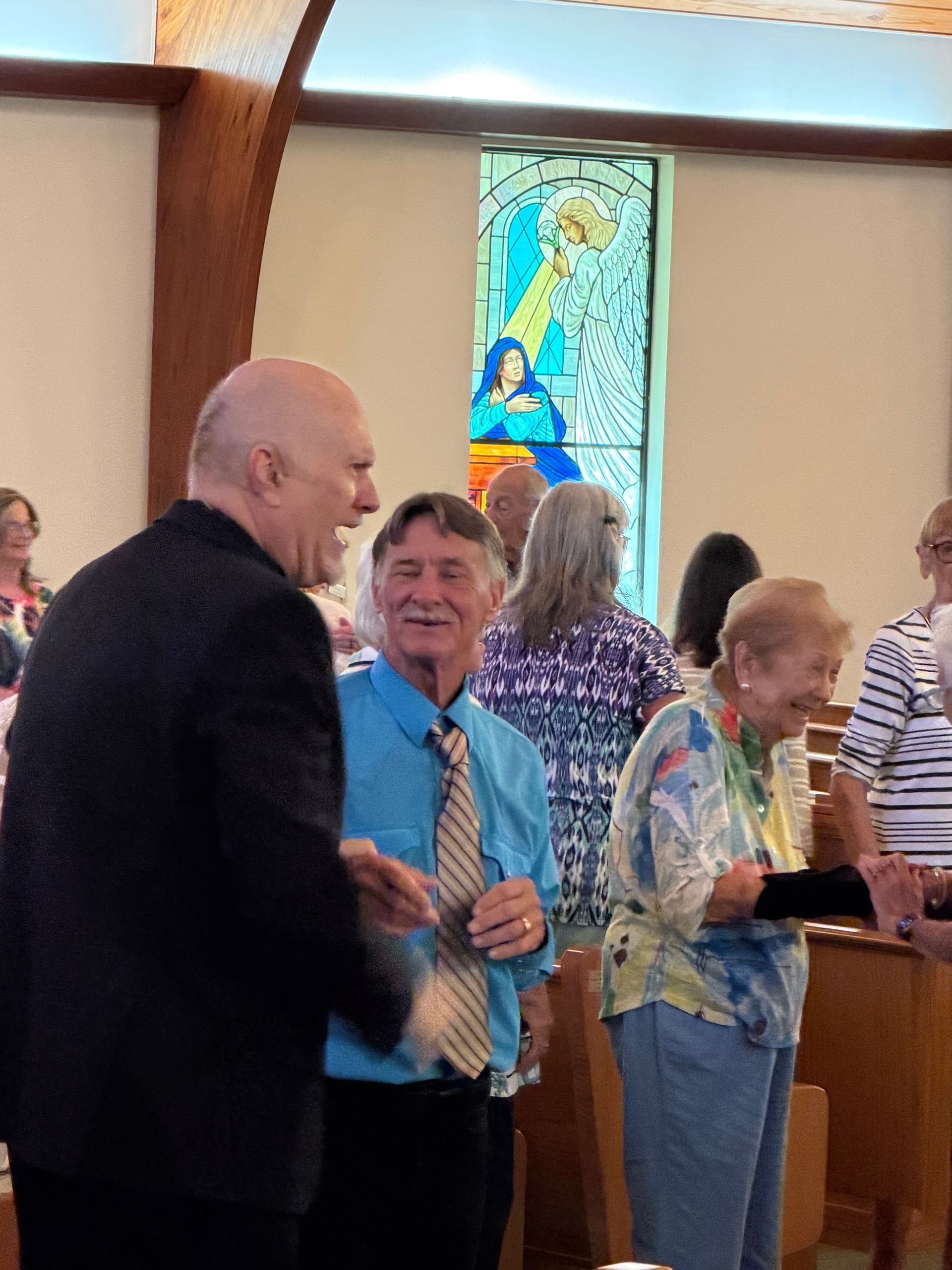 People praying with hands clasped over an open Bible on a table