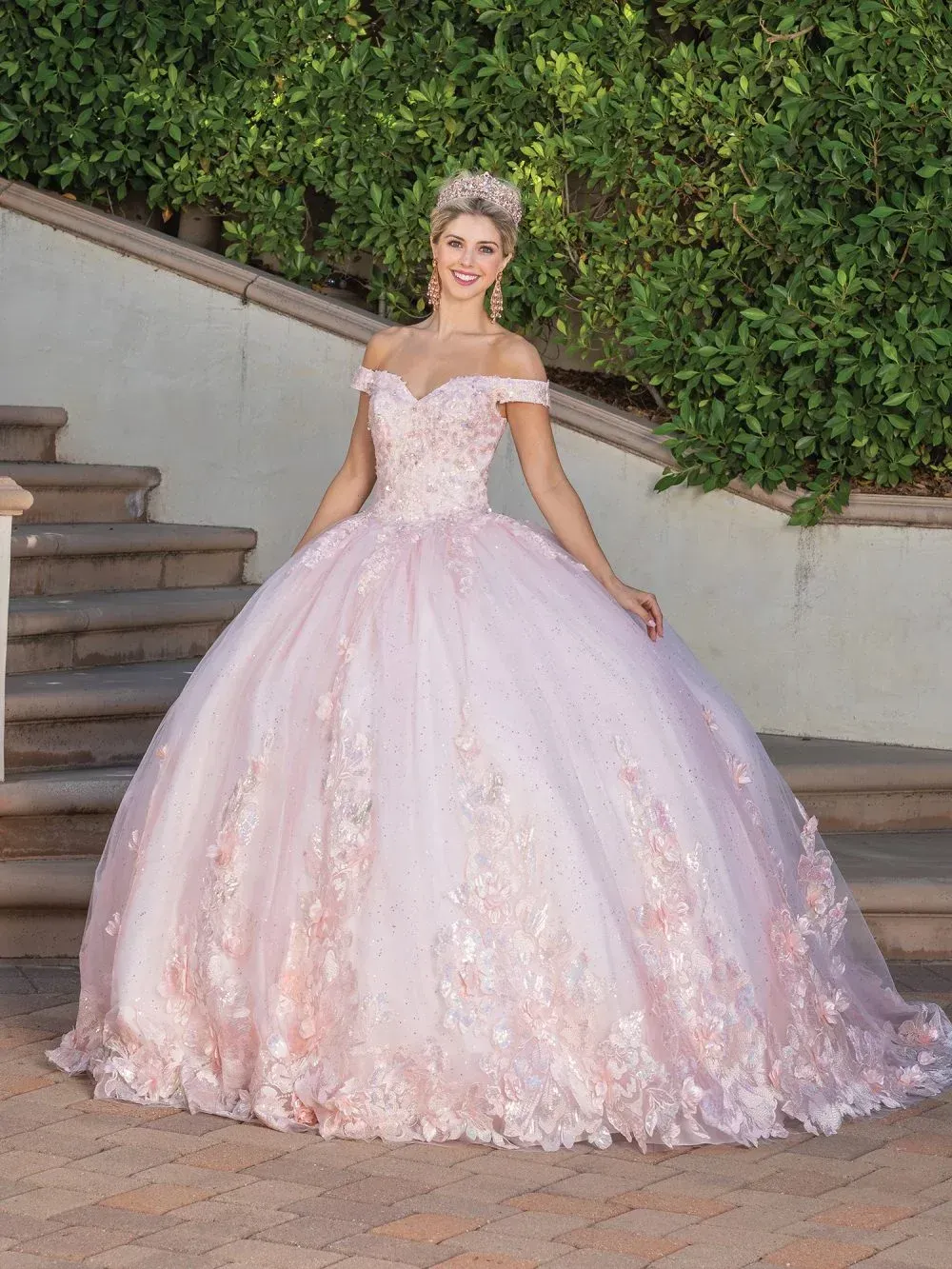 A woman in a pink ball gown is standing on a set of stairs.