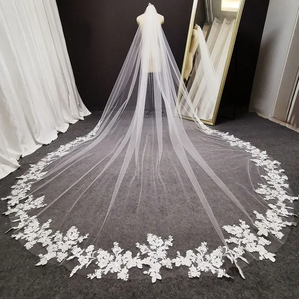 A long white veil with white lace embroidery is on a mannequin