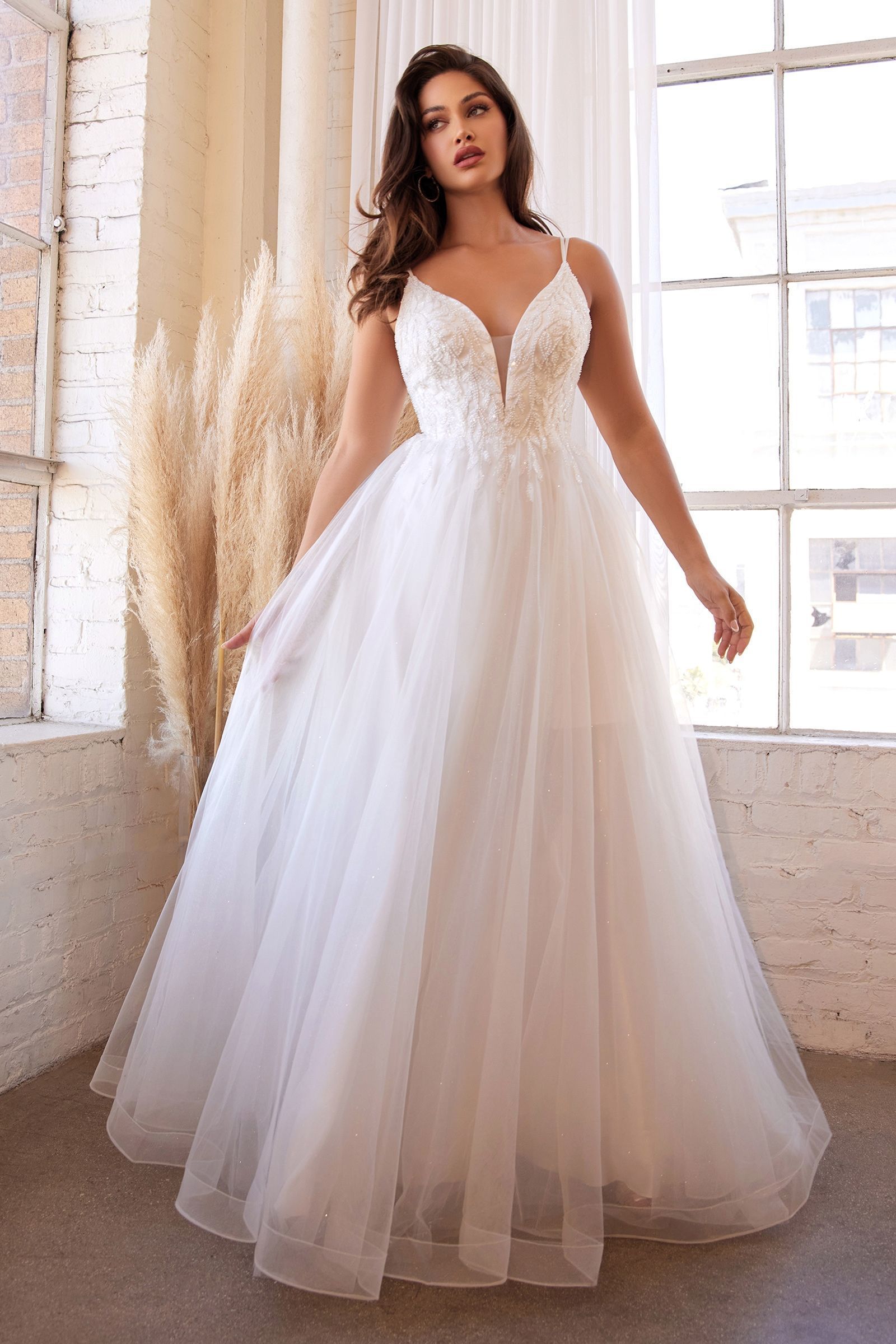 A woman in a white wedding dress is standing in front of a window.