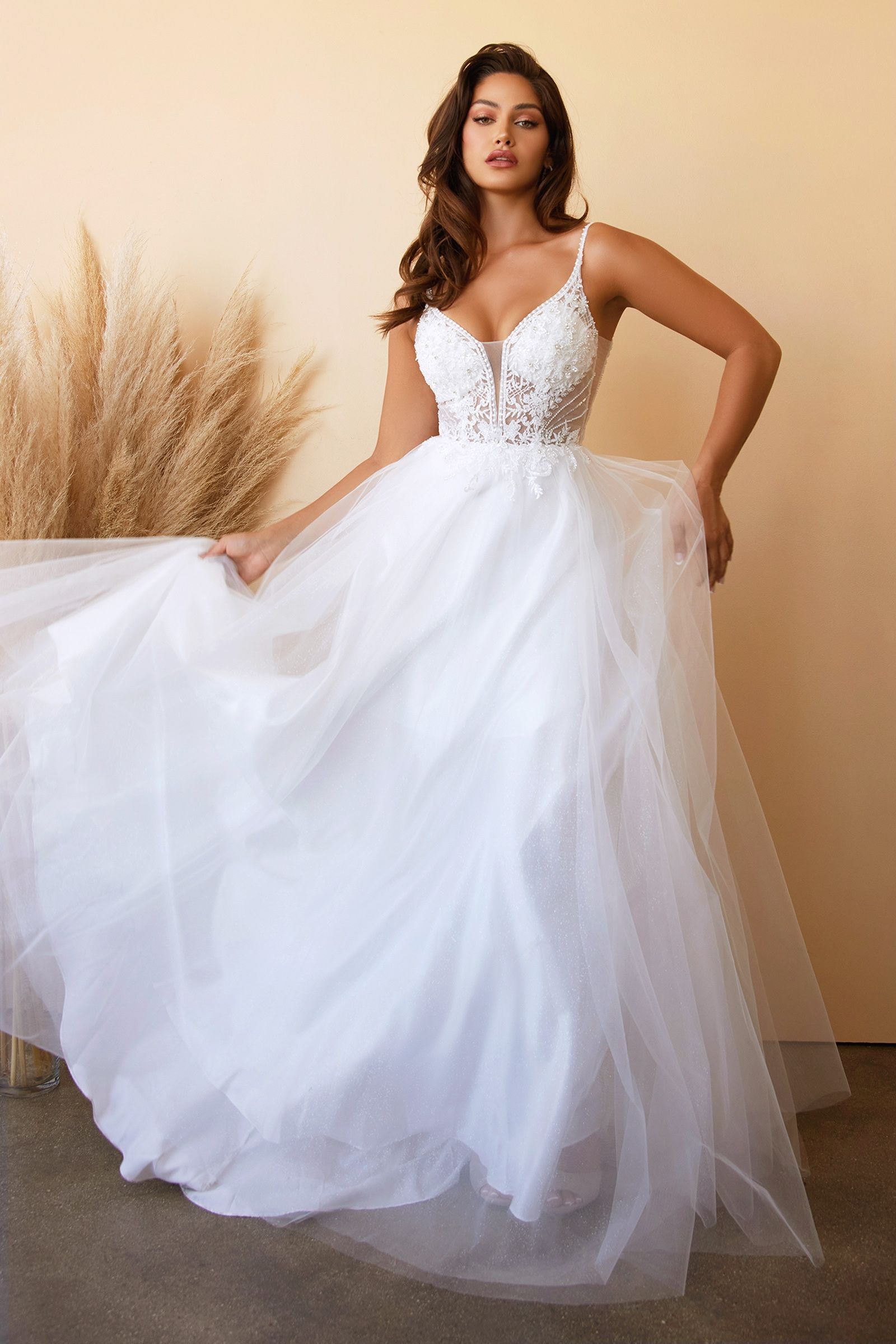 A woman in a white wedding dress is standing in front of a wall.