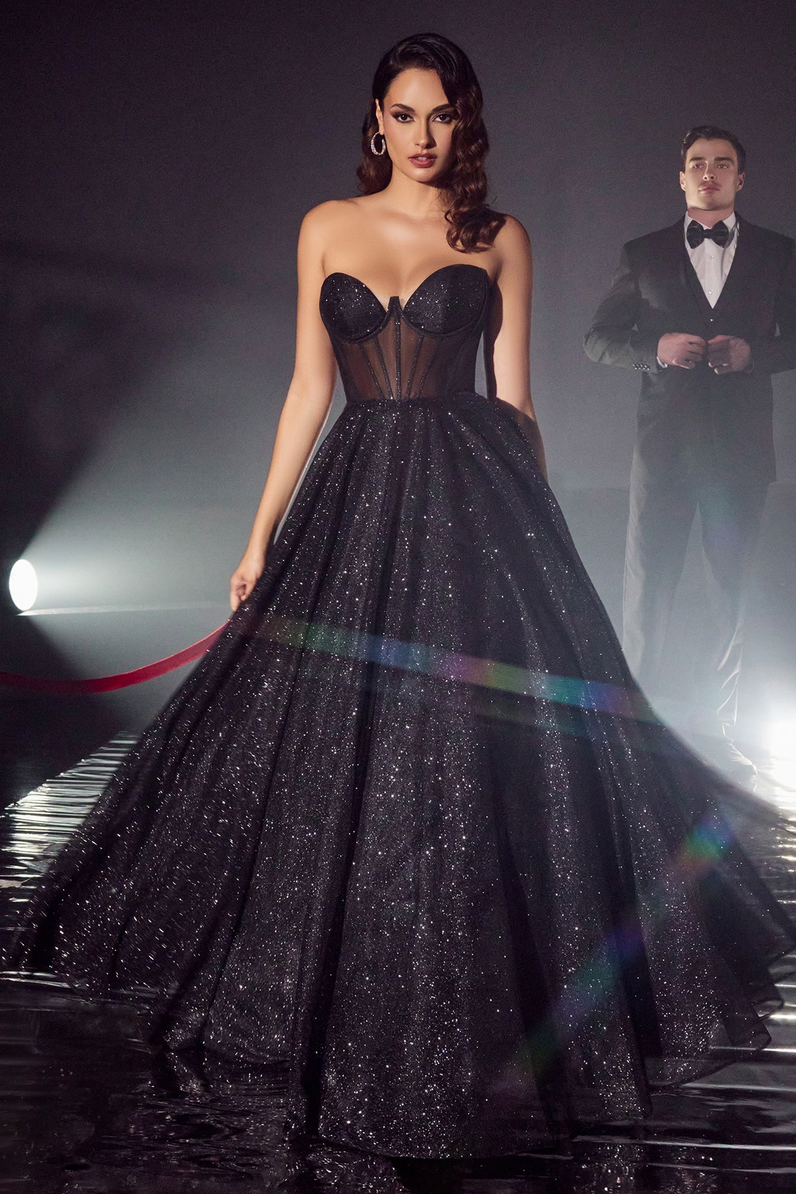 A woman in a black ball gown is standing next to a man in a tuxedo.