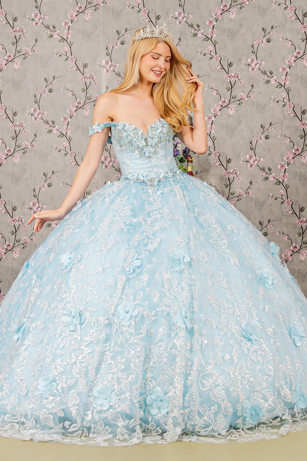 A woman is wearing a light blue ball gown and a tiara.