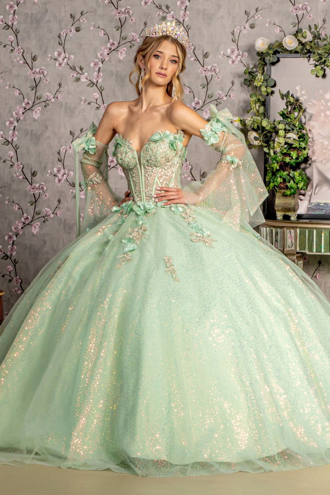 A woman is wearing a green ball gown and a tiara.