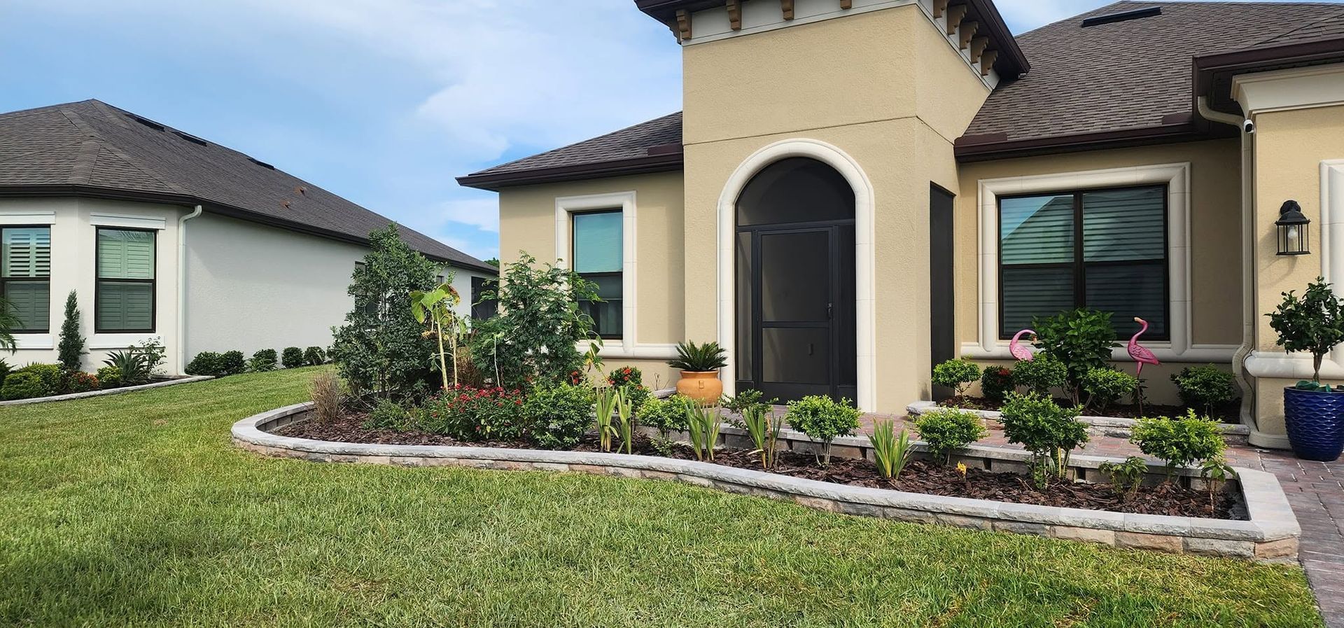 Modern suburban homes with manicured lawns, landscaped gardens, and a front walkway under a cloudy sky