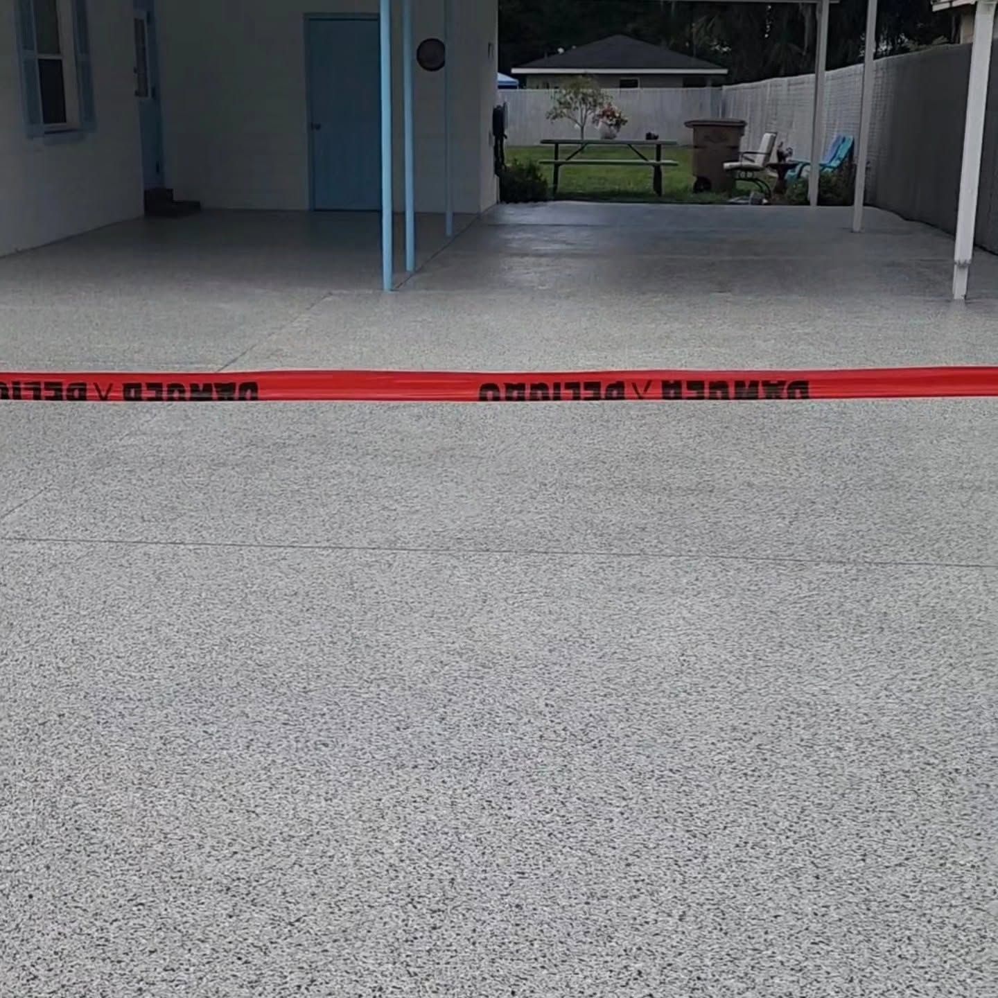 Red caution tape blocking a covered concrete patio area outside a house