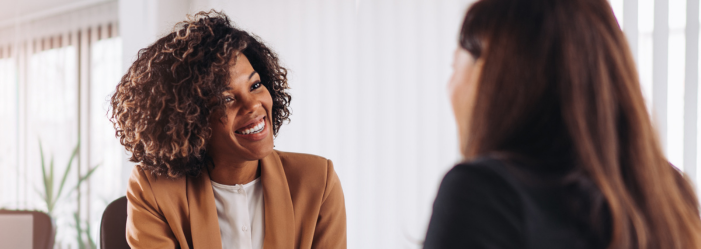 Two people talking face-to-face in a bright office, one smiling and gesturing