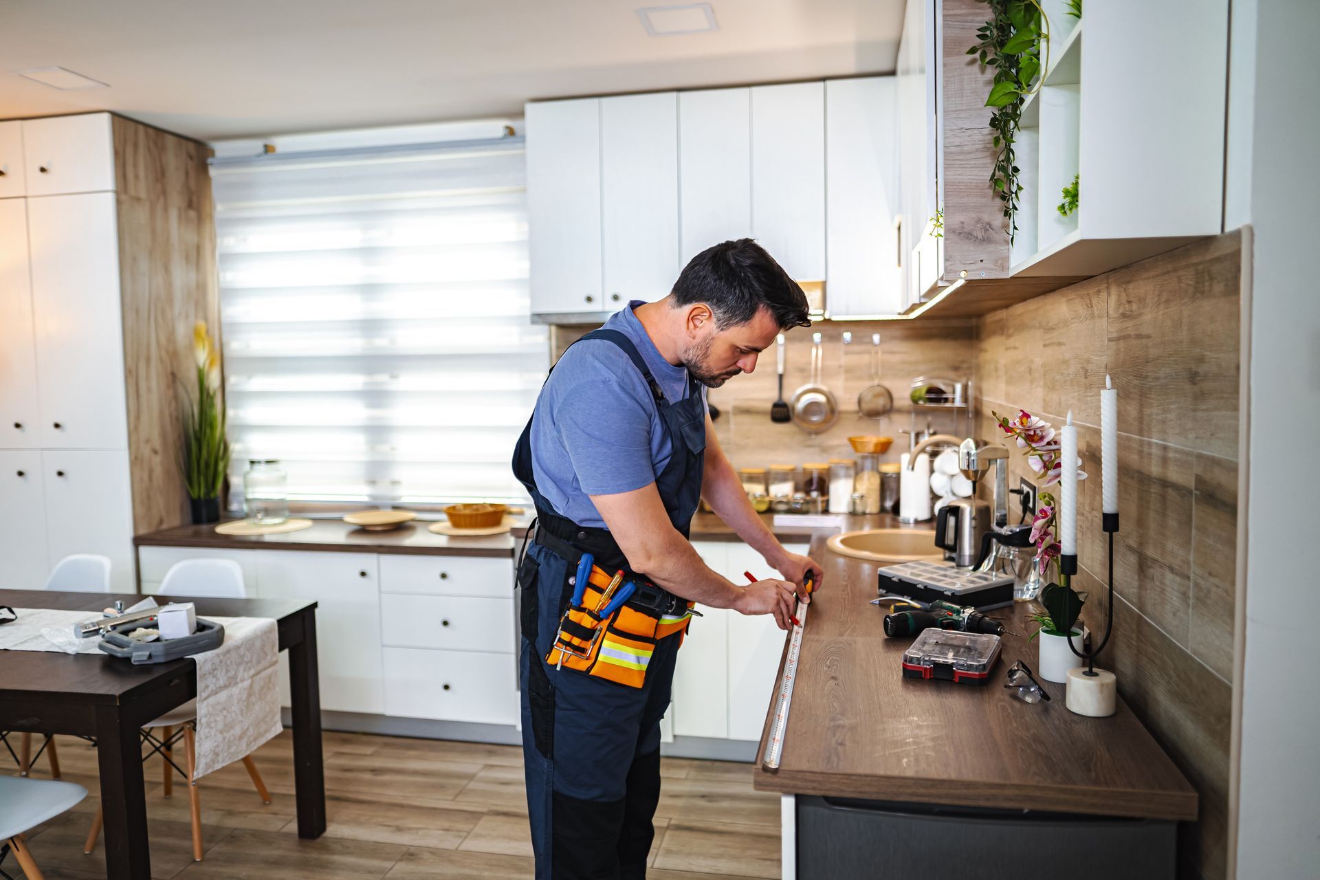 Kitchen remodeling contractor measuring a countertop in a bright white kitchen