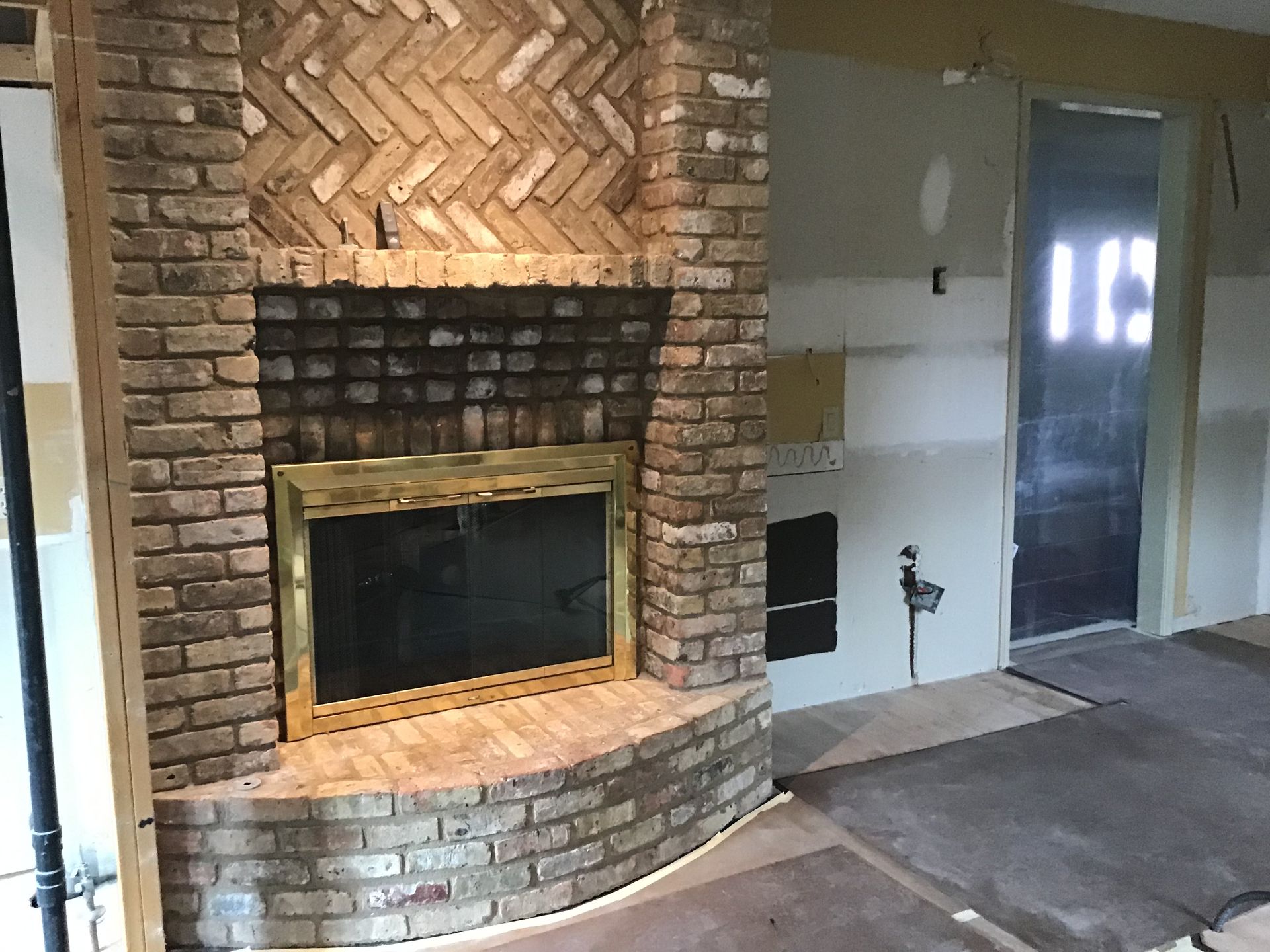 Interior room with brick fireplace and unfinished walls beside a doorway
