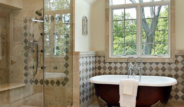 Bathroom with glass shower, freestanding tub, and large window overlooking greenery