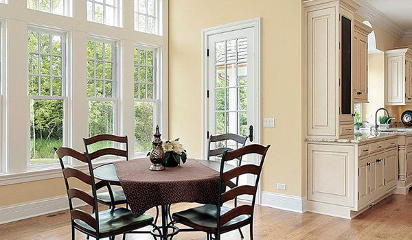 Sunlit dining area with round table, chairs, and a view into a bright kitchen