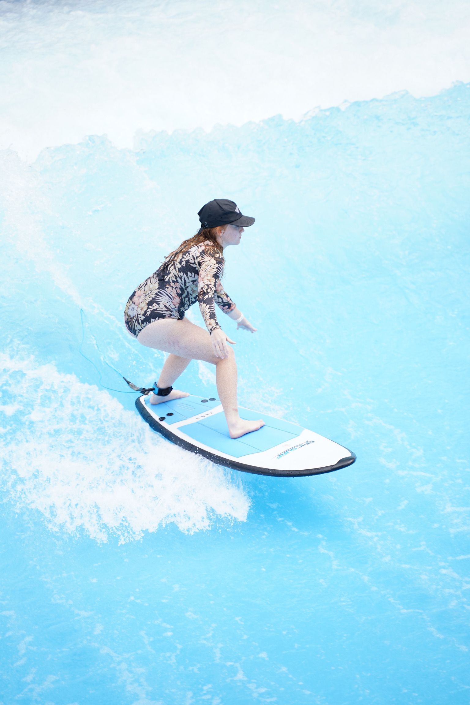 Surfer riding a wave on a surfboard in bright blue water on the EpicSurfUSA