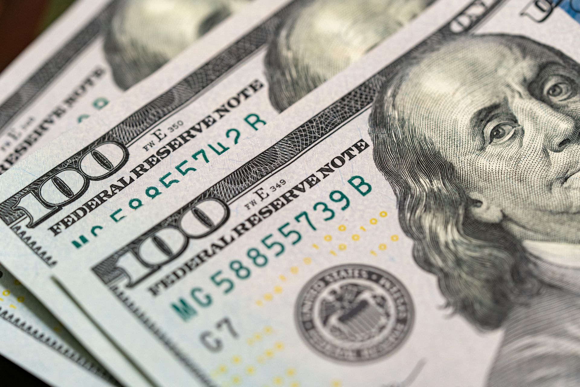 A close up of a stack of 100 dollar bills on a table.