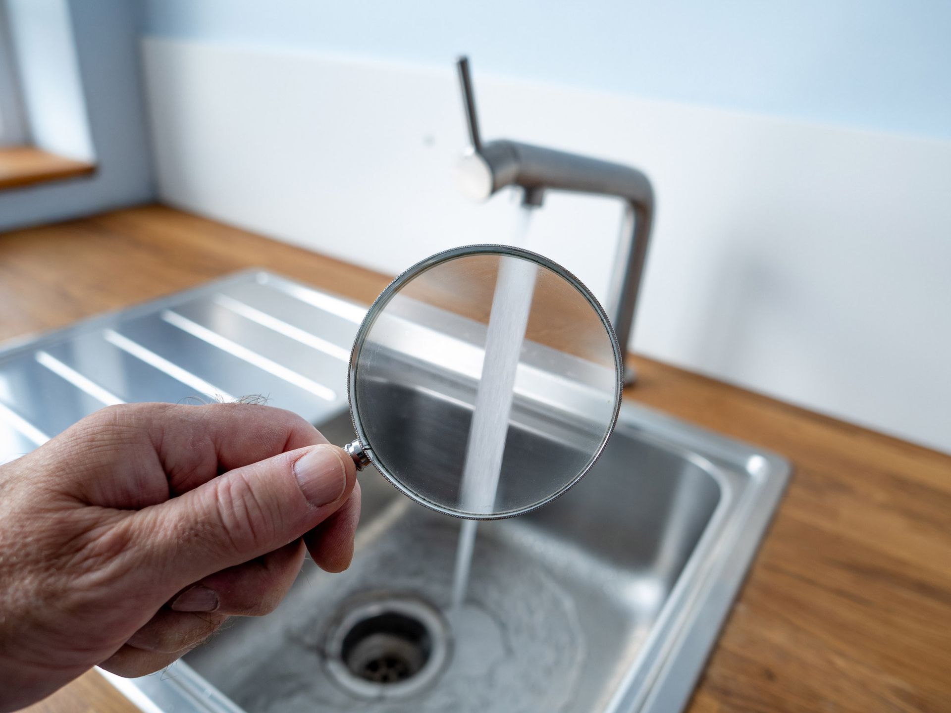 A stream of tap water in Creve Coeur, MO being looked at using a magnifying glass by Our Free Water