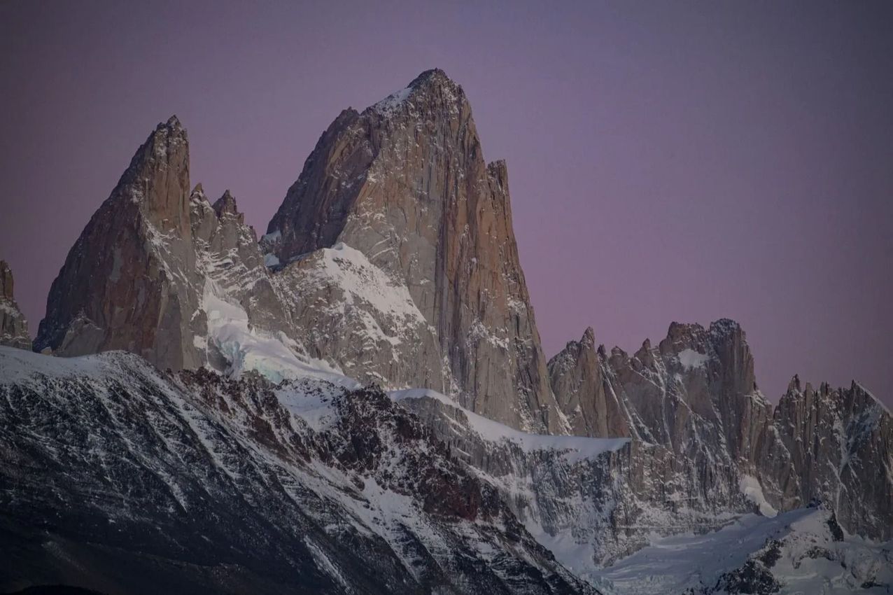 Cumbres nevadas al atardecer bajo un cielo púrpura