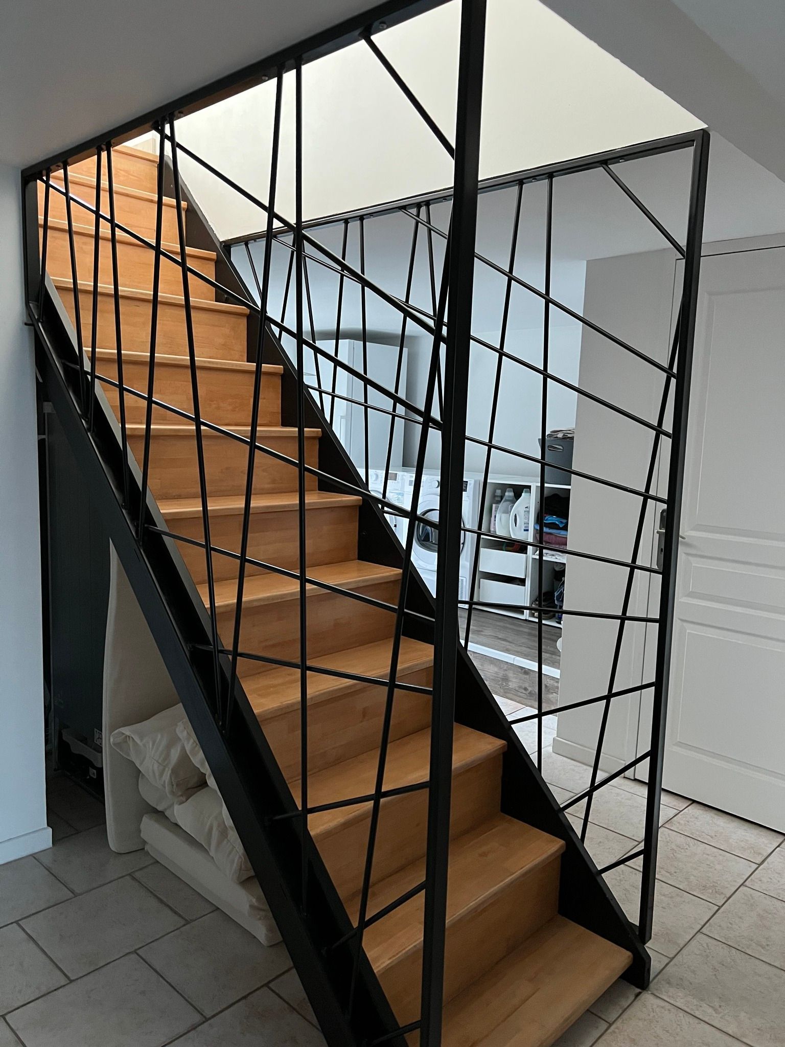 Escalier en bois avec rampe en métal noir.
