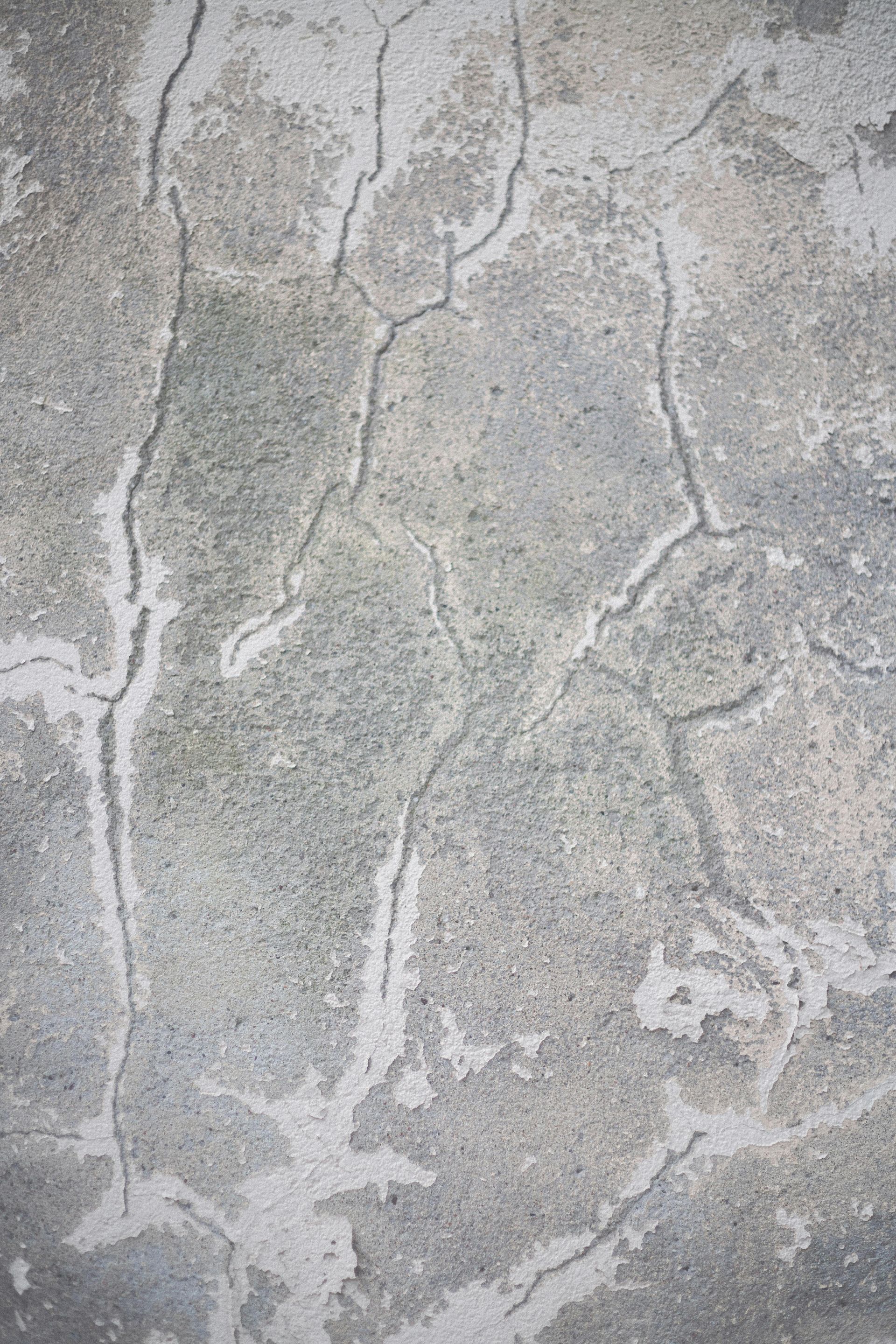 Un gros plan d'un mur en béton avec des fissures.