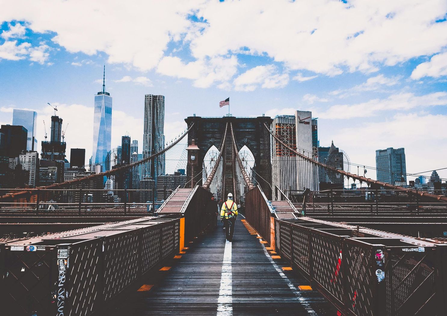 A man is walking across a bridge in new york city.