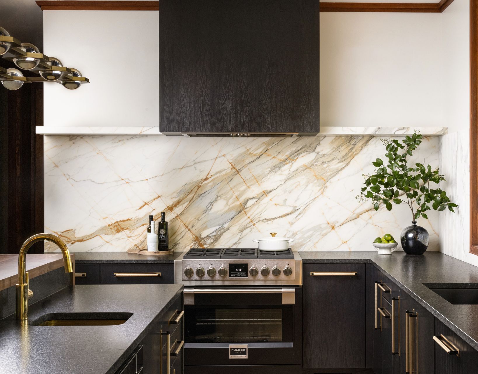 A kitchen with black cabinets , a stove , a sink , and a large island.