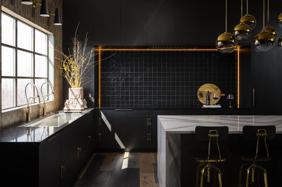 A kitchen with black cabinets and a marble counter top.