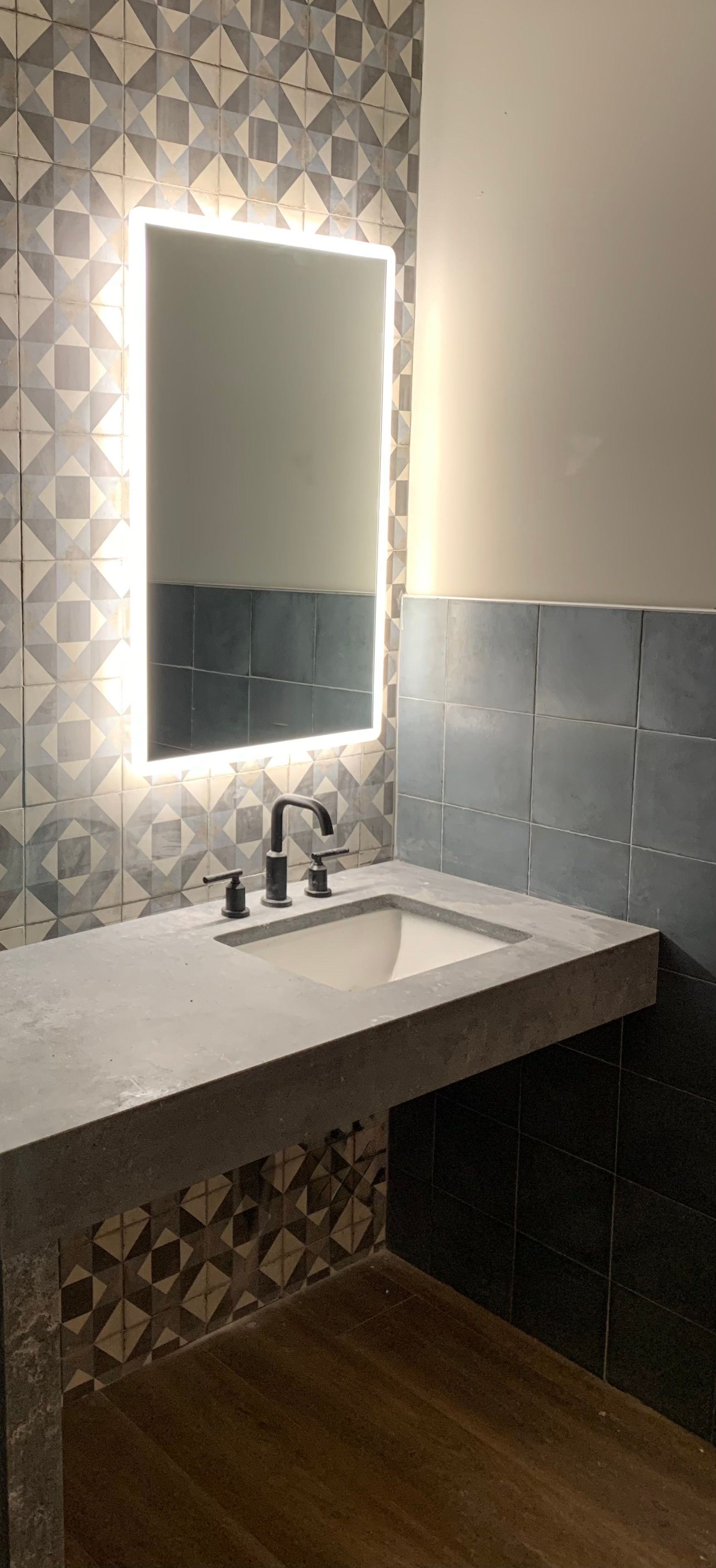 A modern bathroom with a backlit mirror above a sink