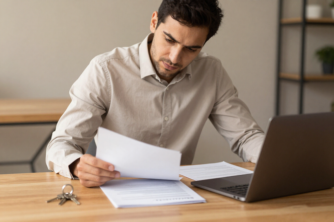 Property manager reviewing paperwork with laptop and keys