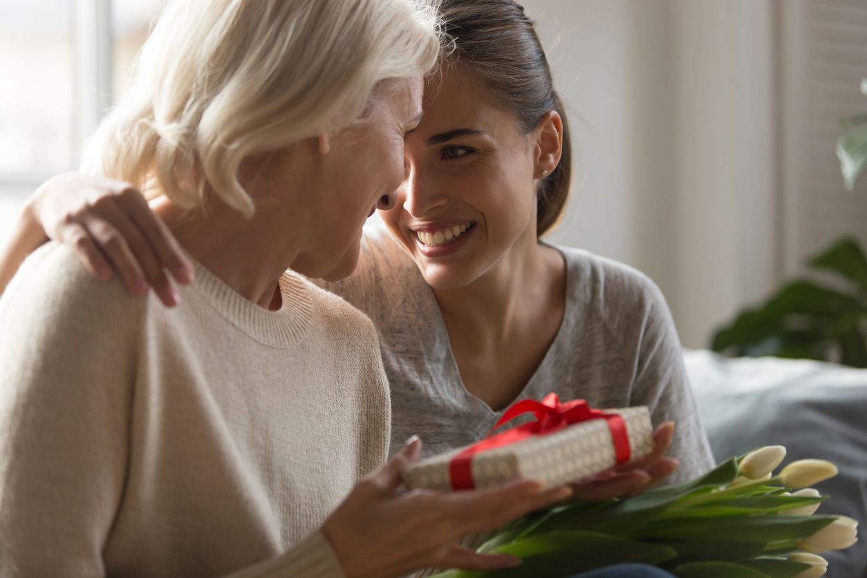 Daughter giving her mom gifts and flowers for Mother’s Day
