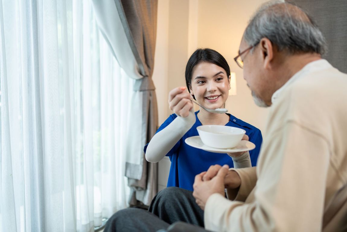 nurse in home helping feed male patient soup
