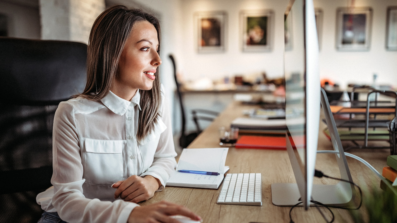 A woman is sitting at a desk in front of a computer.
