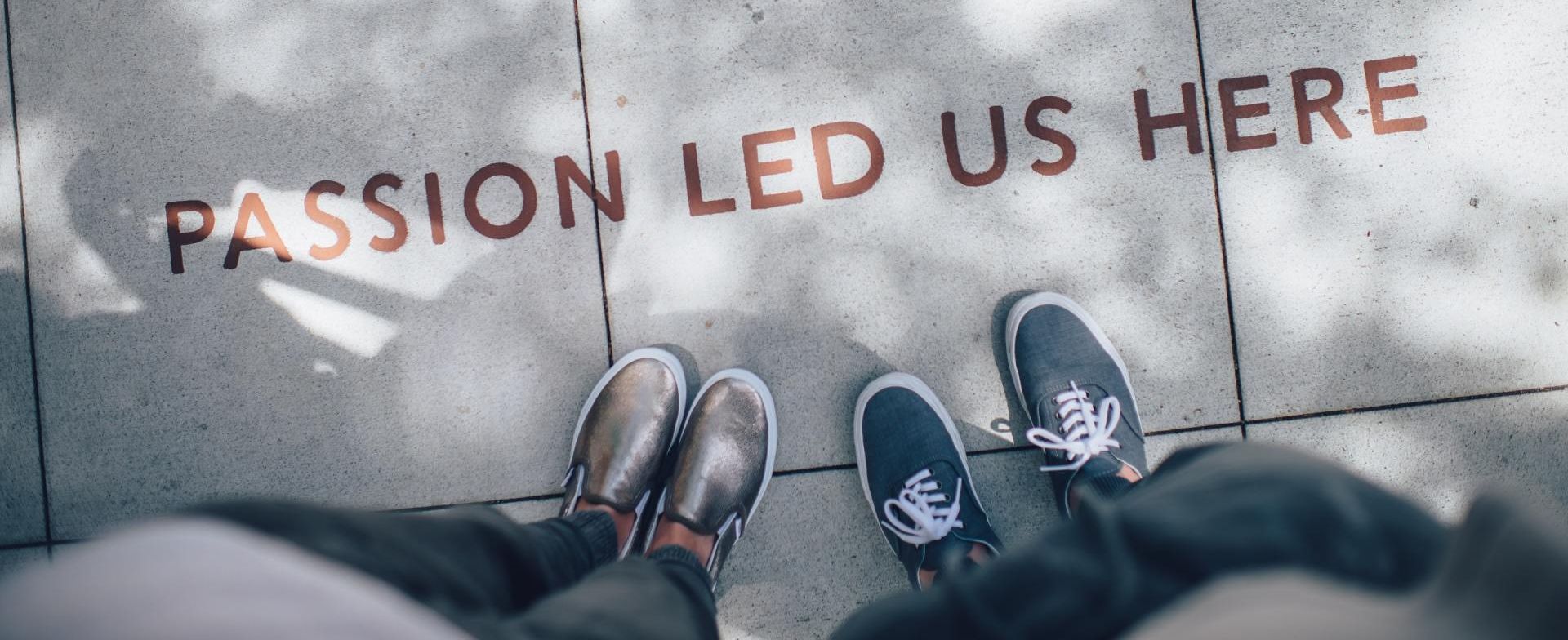 A couple of people standing on a sidewalk with the words passion led us here written on the ground.