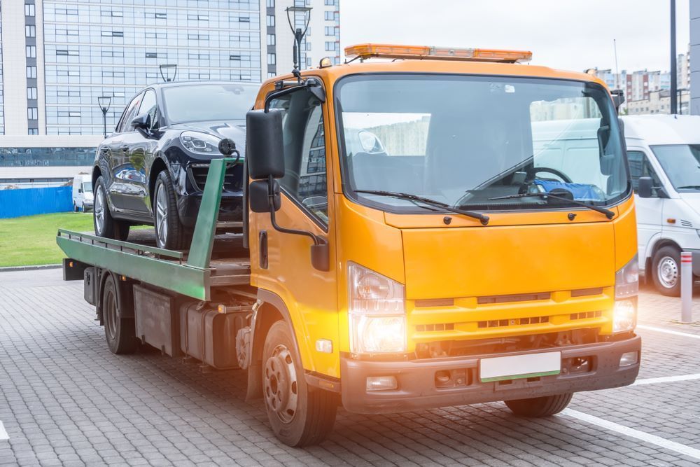 A Tow Truck is Towing a Car in a Parking Lot — Aura Towing Service in Baringa, QLD