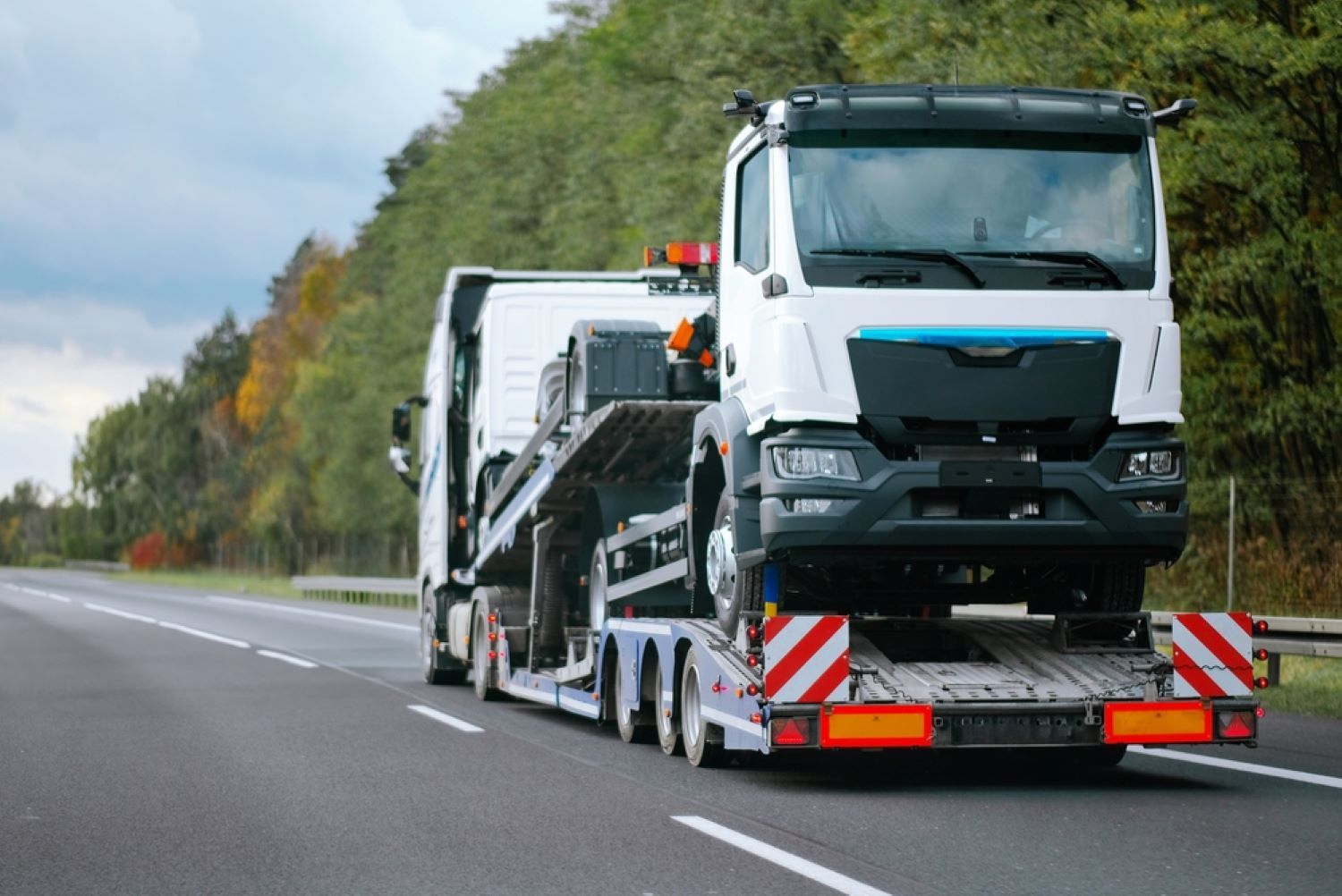 A Semi Truck is Driving Down a Highway With a Car — Aura Towing Service in Maroochydore, QLD 
