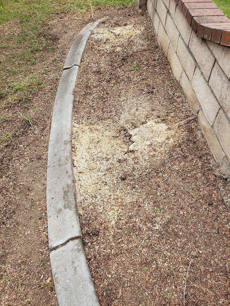 A concrete curb is sitting next to a brick wall