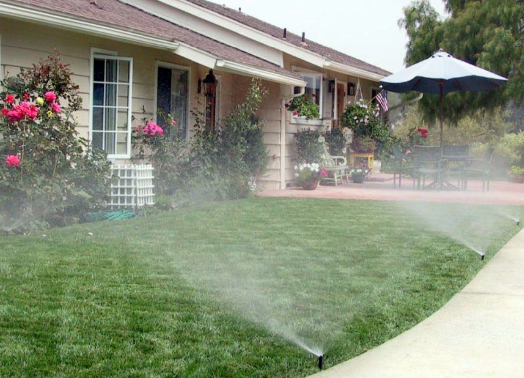 A lawn with sprinklers spraying water in front of a house