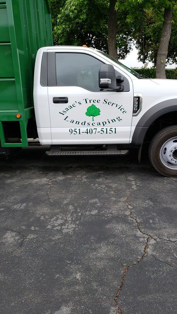 A white truck with a green dumpster attached to it is parked in a driveway