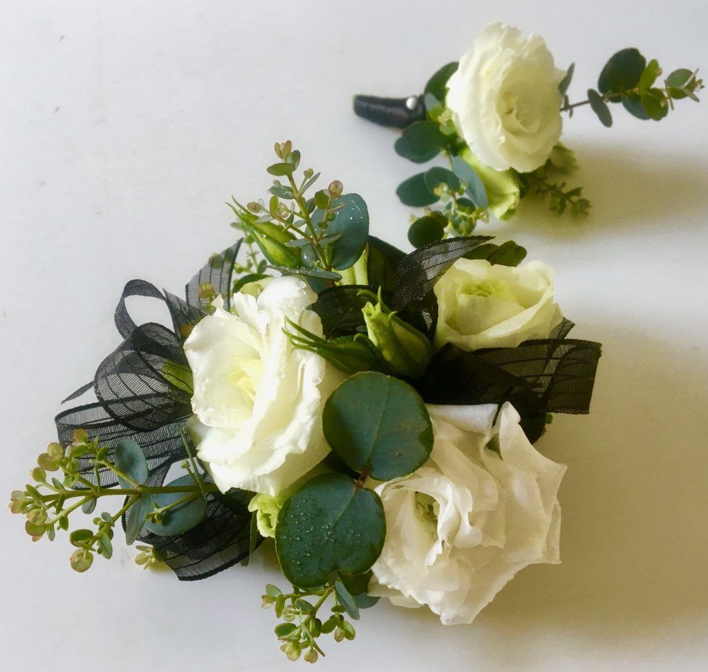 White rose floral arrangement with greenery and black ribbon on a light background