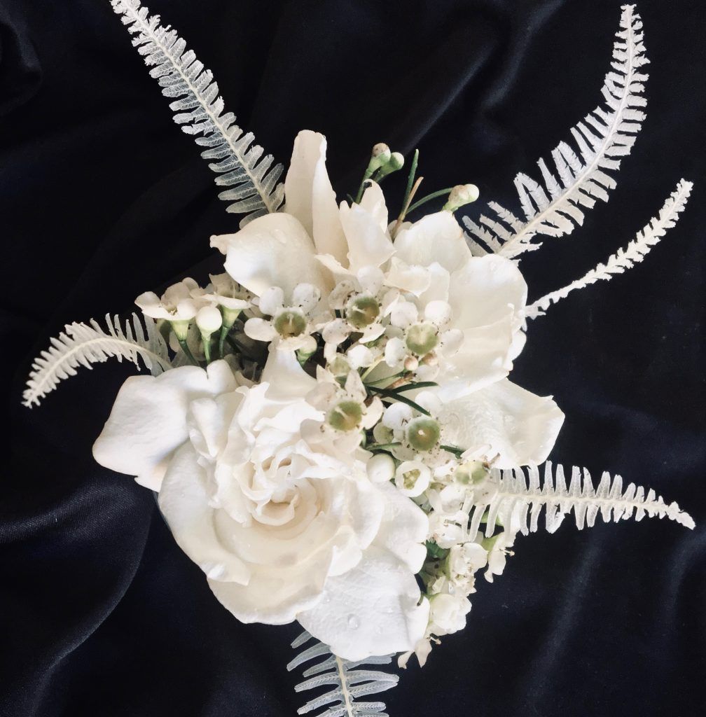 White floral bouquet with roses and fern-like greenery on a black background