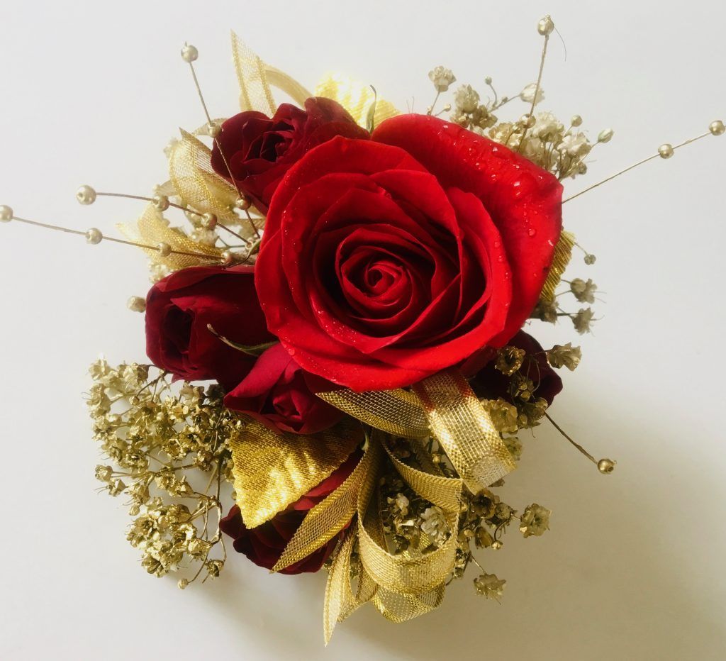 Red rose bouquet with gold ribbon and baby's breath on a light background