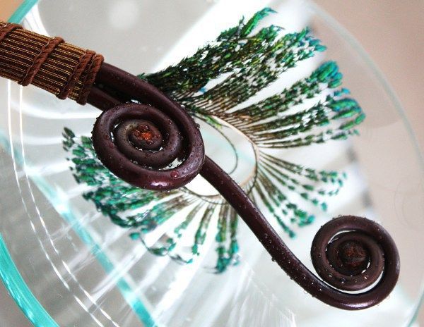 Brown spiral hairpin on a clear glass plate with green leafy pattern