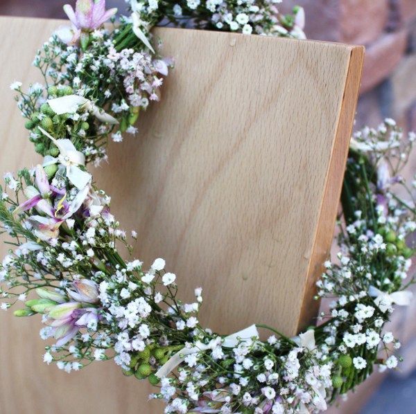 Wooden plaque framed by a pastel purple and white floral wreath