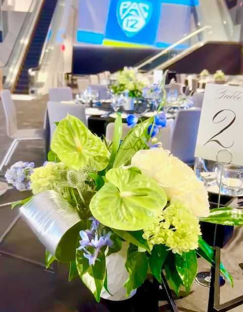 Las Vegas corporate event of bright green and white floral centerpiece and Pac-12 backdrop