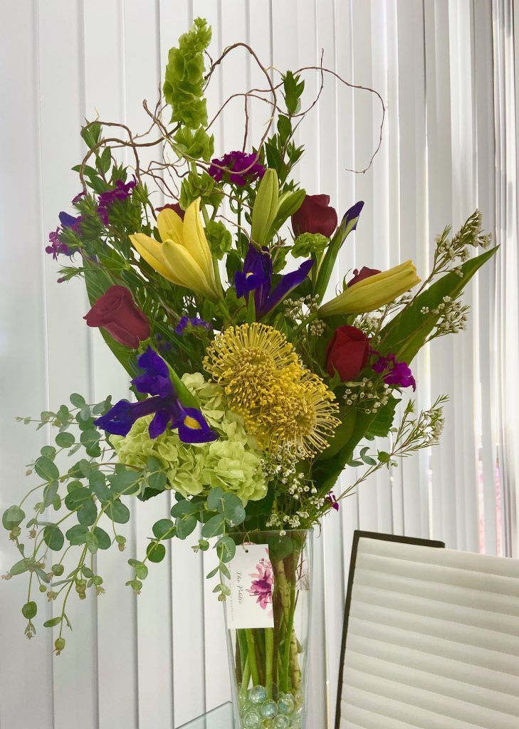 A vase filled with flowers is sitting on a table next to a chair.