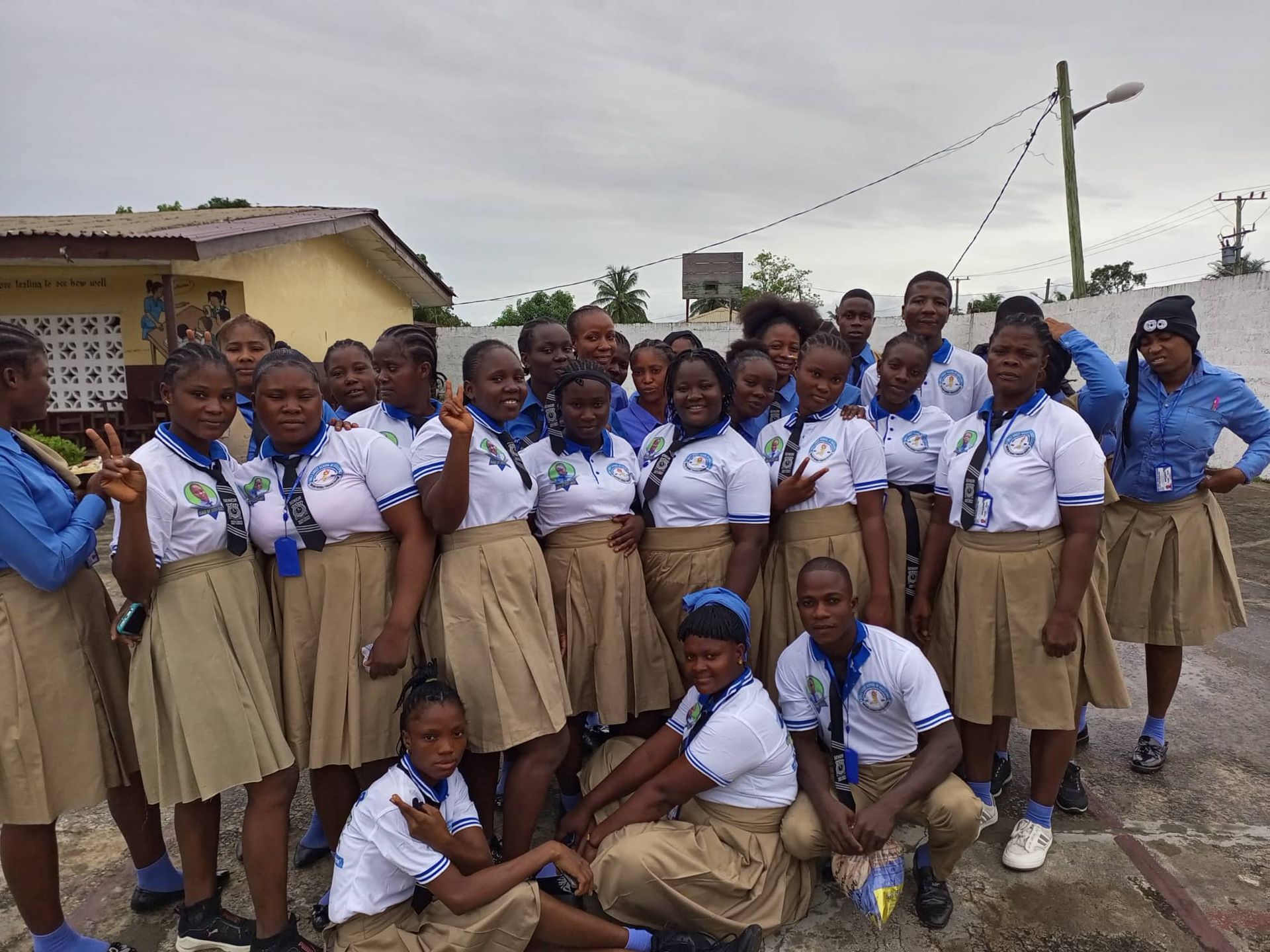 Group of students in blue-and-white uniforms posing outdoors on a roadside