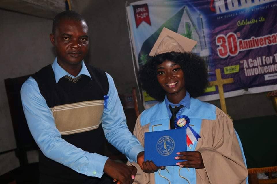 Two people at a ceremony, one holding a blue certificate plaque, with a 30th anniversary banner behind them