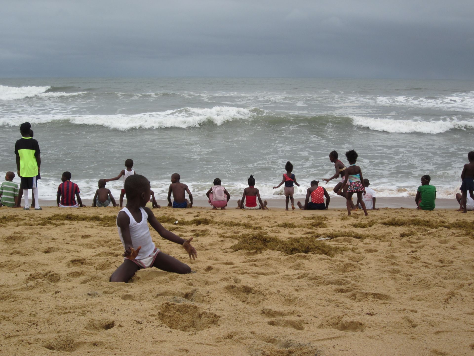 Children playing on a sandy beach with waves crashing in the background